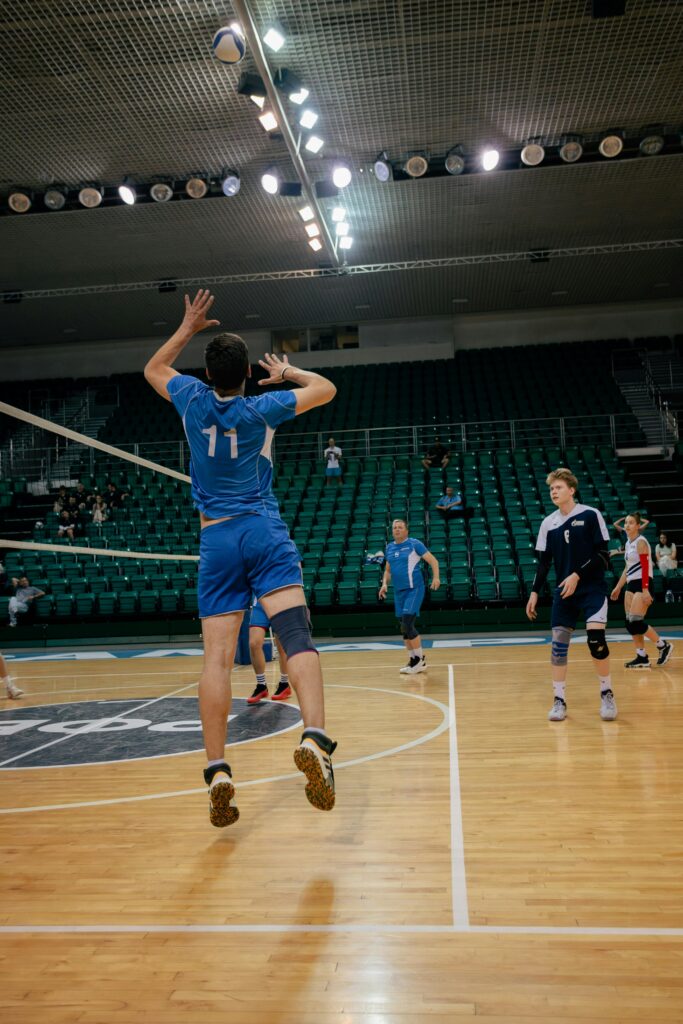 Dynamic action shot of a volleyball player serving indoors during a competitive match.