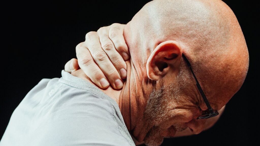 Side view of senior man holding neck with visible discomfort, highlighting neck pain relief.