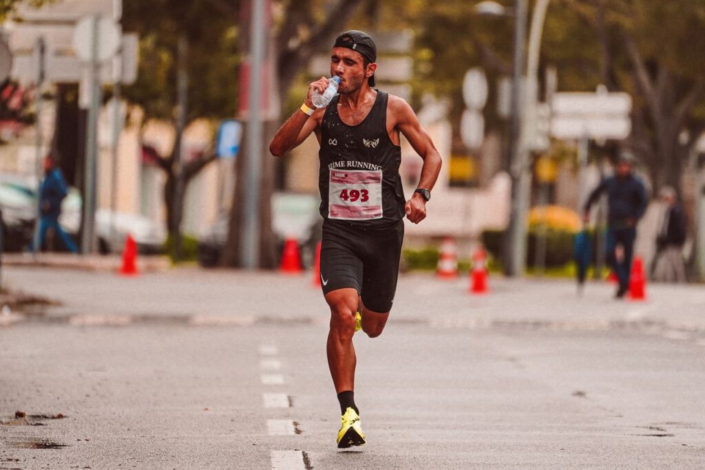 Athlete running in a marathon, staying hydrated. Outdoor city street scene.