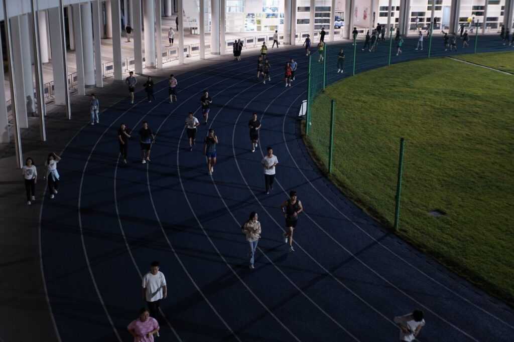 A group of people jogging on an outdoor track in the evening, showcasing urban fitness culture.